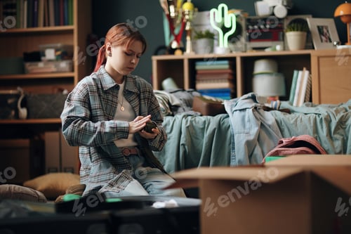 Preview: Teenage Caucasian Girl Sitting on Floor While Packing Belongings