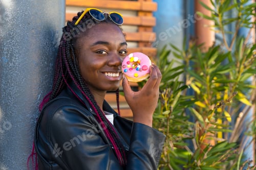 Preview: Cool african woman with a multicolored sweet doughnut
