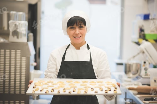 Preview: Baker carrying tray of pastries in kitchen