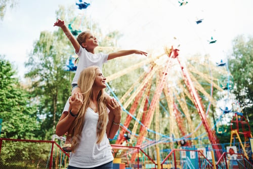 Preview: little girl her mother have a good time in the park together near attractions