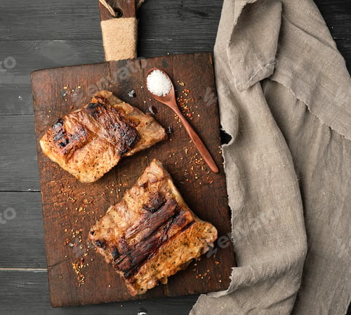 Preview: Grilled pork ribs on a brown wooden cutting board,