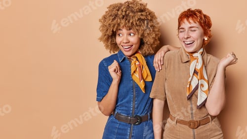 Preview: Studio shot of positive two women dressed in fashionable sarafans with kerchief around neck look