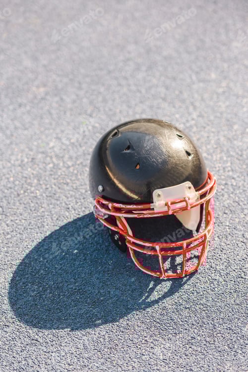Preview: high angle view of american football helmet lying on asphalt