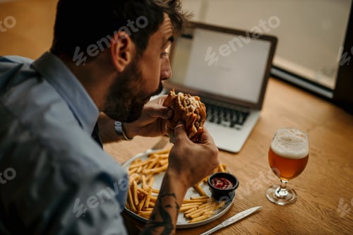 Preview: Office worker eating burger and french fries at lunch break in restaurant