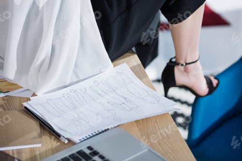 Preview: cropped shot of fashion designer sitting on work table with sketches