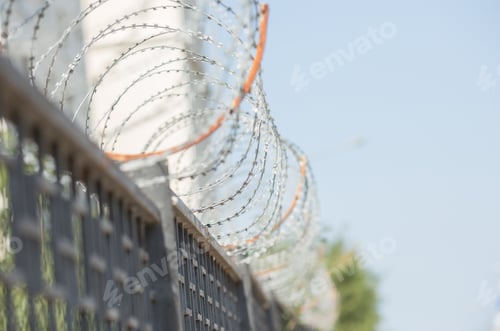 Preview: metal fence with barbed wire on a blue sky background
