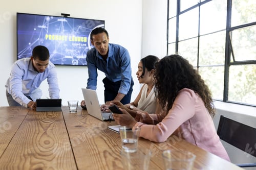 Preview: In conference room, business team using digital devices collaborating on project