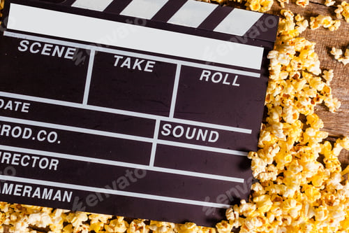Preview: Film clapperboard and popcorn lay on wood surface for movie night activity