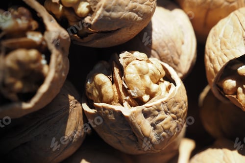 Preview: A scoop of walnuts, a superfood, rests on a stack of nuts seeds