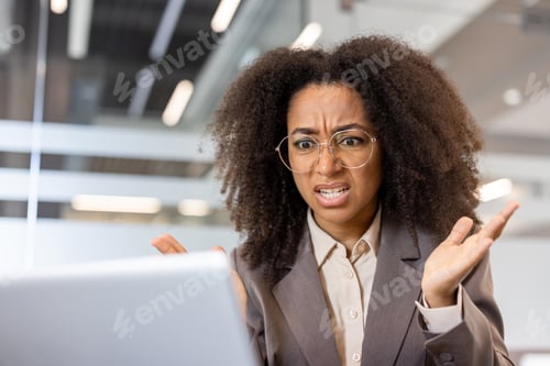 Vista previa: Confused African American businesswoman working on laptop in modern office
