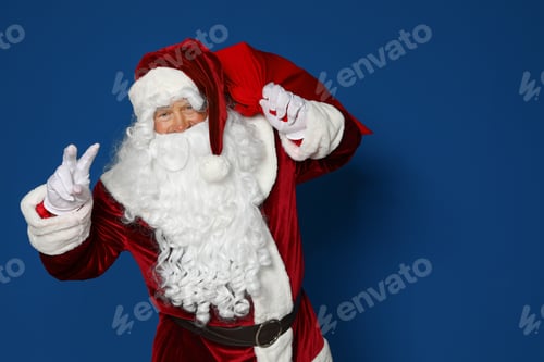 Preview: Happy authentic Santa Claus with bag full of gifts on blue background. Space for text