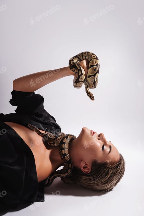 Vista previa: Hermosa mujer con serpientes pitón deslizándose elegantemente sobre su cuerpo