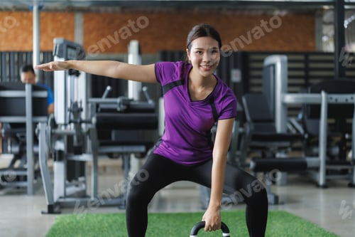 Preview: Young asian woman performing kettlebell workout in gym for fitness training