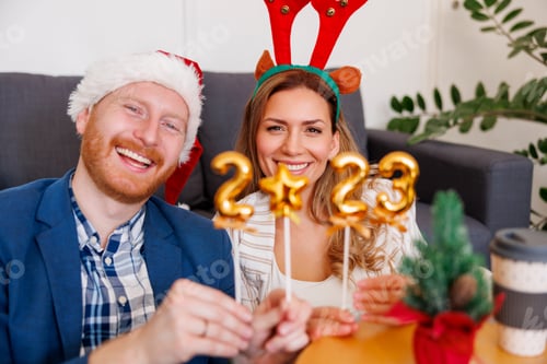 Preview: Business people holding numbers 2023 while celebrating Christmas at the office
