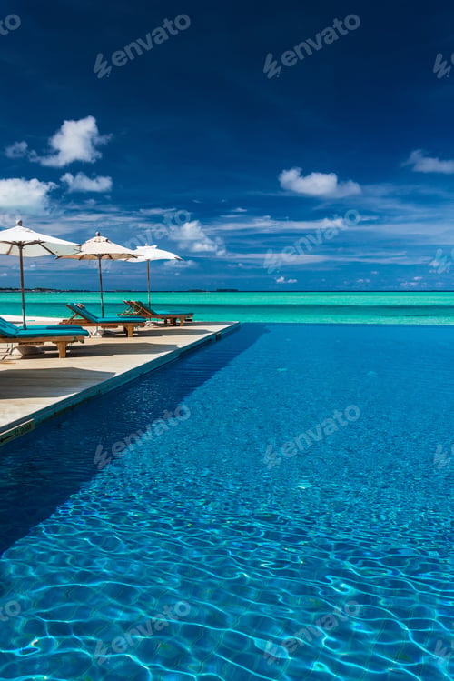Preview: Infinity swimming pool on the beach of tropical island with whit