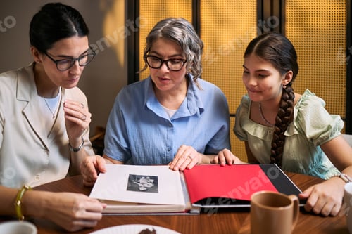 Preview: Two Women and Teenager Girl Reviewing Family Photo Album