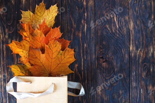 Preview: Gift bag with golden autumn leaves on dark wooden background top view
