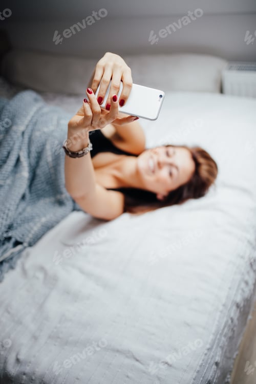 Preview: Women taking selfie while laying in bed