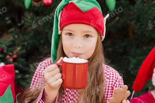 Preview: Merry Christmas. Portrait of two funny children girls in Santa hat eating gingerbread cookies