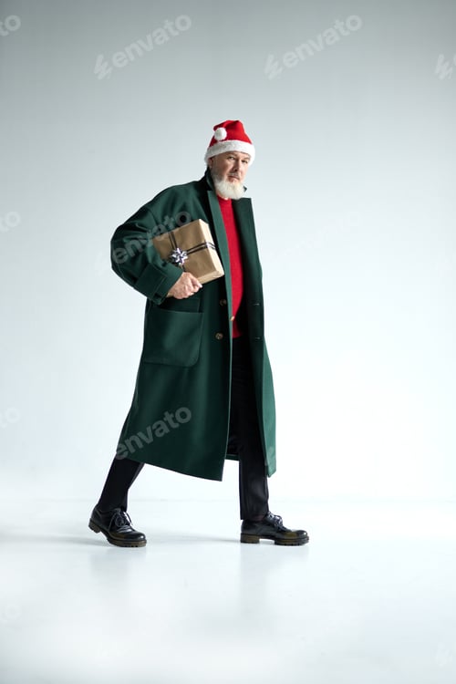 Preview: Full length shot of fashionable mature man with Christmas hat wearing stylish outfit looking at