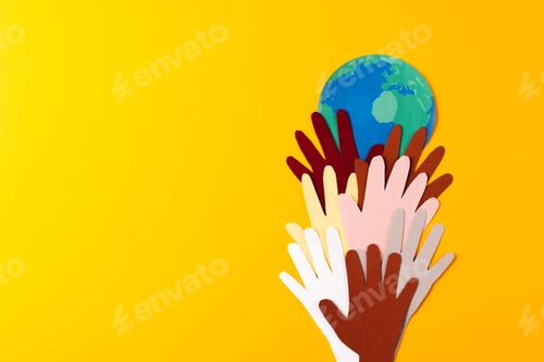 Preview: Paper cut out of multi coloured hands and globe with copy space on yellow background