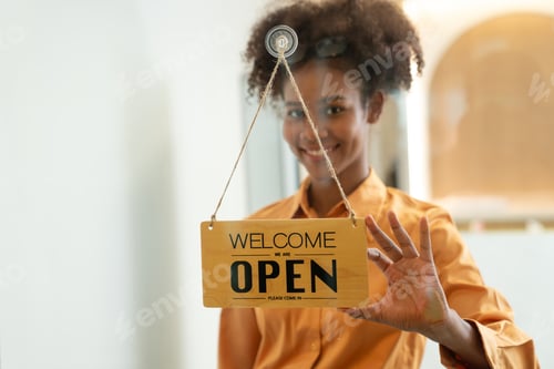 Preview: Woman hanging open sign on door.