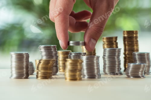 Preview: cropped view of person stacking coins on table, investment concept