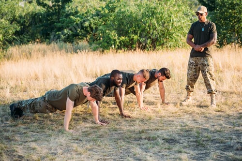 Preview: tactical instructor in sunglasses examining multicultural soldiers doing push ups on range
