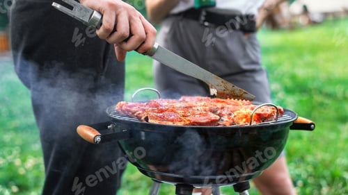 Preview: Young couple frying meat on the grill