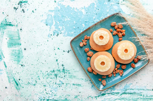 Preview: top view delicious cakes with dried pineapple rings and sweet nuts on light-blue background bake