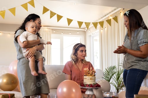 Preview: Celebrating birthday, woman holding cake with candles while friends gather around