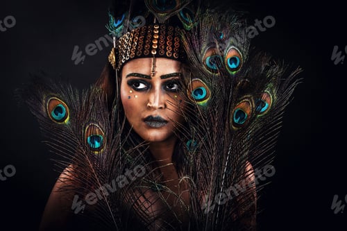Preview: Beautiful woman dressed in a peacock dress poses in the studio