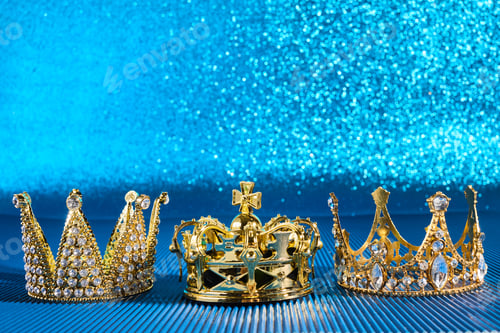 Preview: Epiphany Day or Dia de Reyes Magos concept. Three gold crowns on blue sparkling background