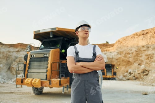 Preview: Posing for a camera. Worker in professional uniform is on the borrow pit at daytime