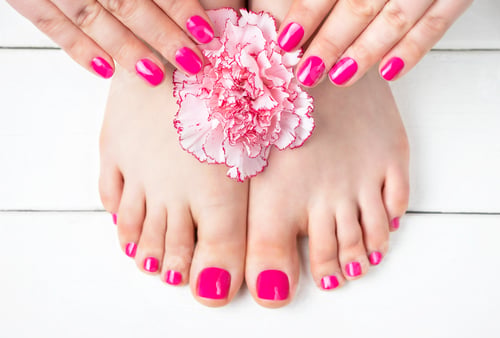 Preview: Pink manicure and pedicure with a flower on white wooden background, top view.
