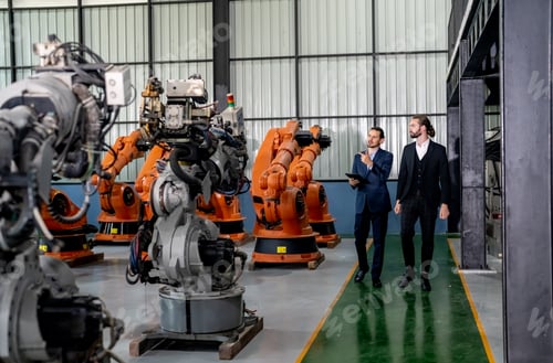 Preview: Businessman pointing toward machinery while walking by coworker at industry