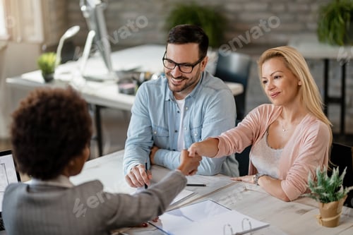Preview: Happy couple handshaking with insurance agent while meeting in the office.
