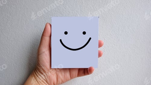 Preview: Hand holding white sticky note paper with smiley icon on white background
