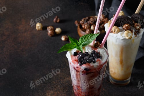 Preview: Delicious berry milkshake garnished with whipped cream, blueberries, dripping jam on dark. Close up.