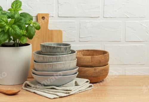 Preview: Kitchen table setting featuring stacked bowls, fresh basil, and cutting board