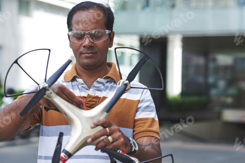 Man Inspecting a Drone Outdoors During the Day