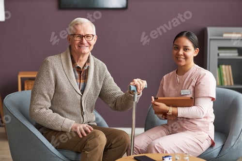 Preview: Senior man and social worker sitting at home