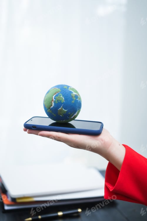 Preview: A young, smiling businesswoman holds a globe her desk, symbolizing global environmental awareness