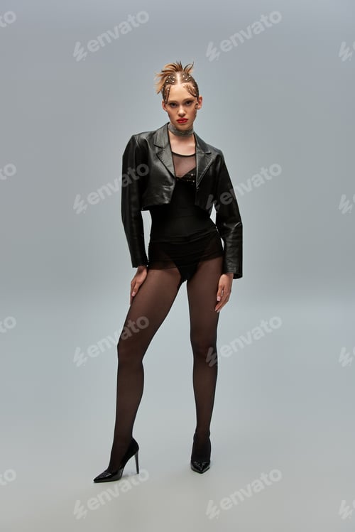 Preview: young woman with pearl pins in hair posing in leather jacket and black tights on grey background