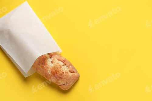 Preview: Paper bag with fresh baguette on yellow background, top view. Space for text