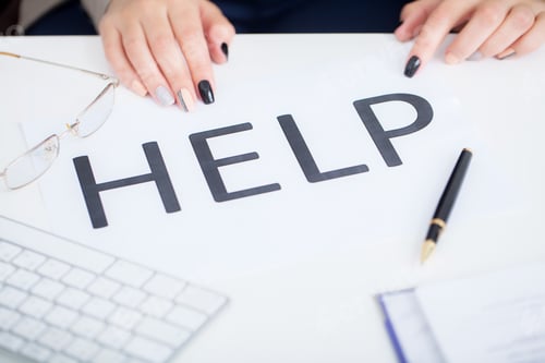 Preview: Stressed business woman imploring for help, holding a cardboard with the message Help