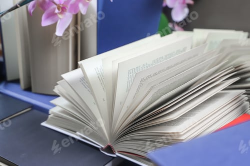 Preview: stack of books, close up. Open book on the table in library. Back to school concept