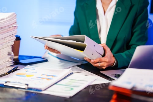 Preview: An Asian businesswoman works overtime,sitting her desk night,searching through numerous documents