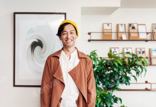 Preview: Male Japanese professional standing in a co-working space, smiling at camera.