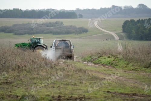 Preview: large vehicle driving on a mud track, tractor in distance